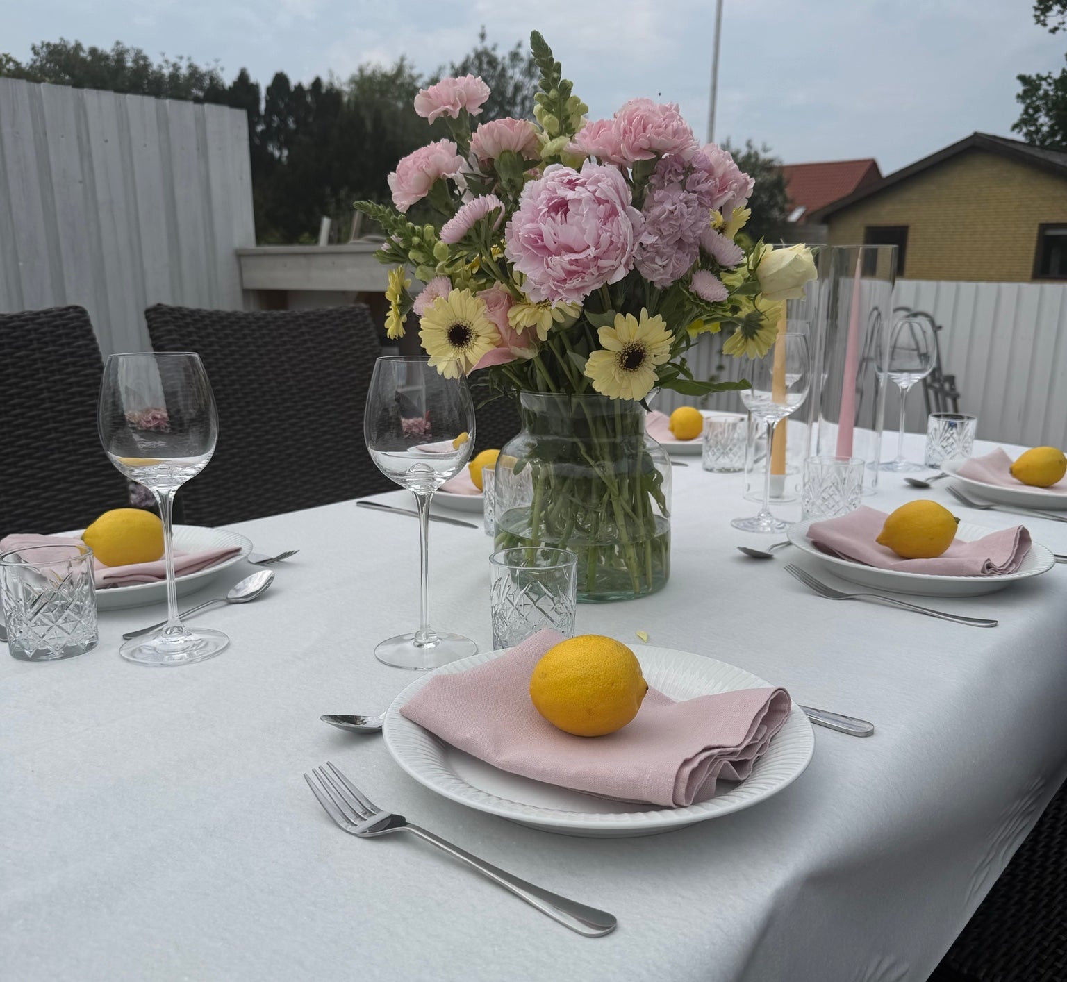 Borddækning med hvid Duni rulledug, lyserøde servietter, citroner og blomster